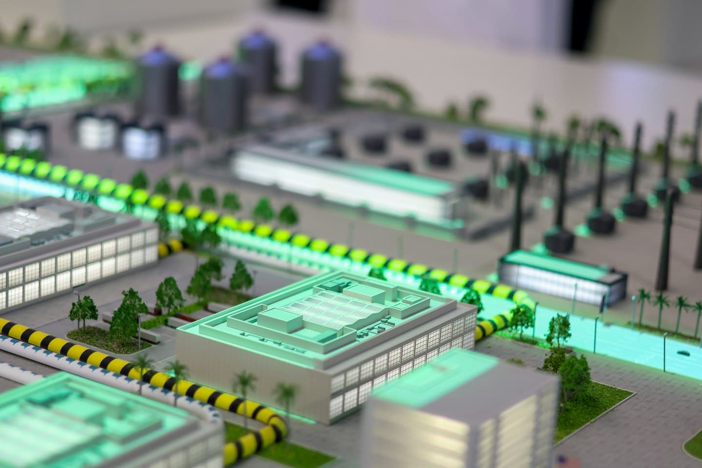 Modello architettonico dettagliato di un complesso industriale con luci verdi luminose.