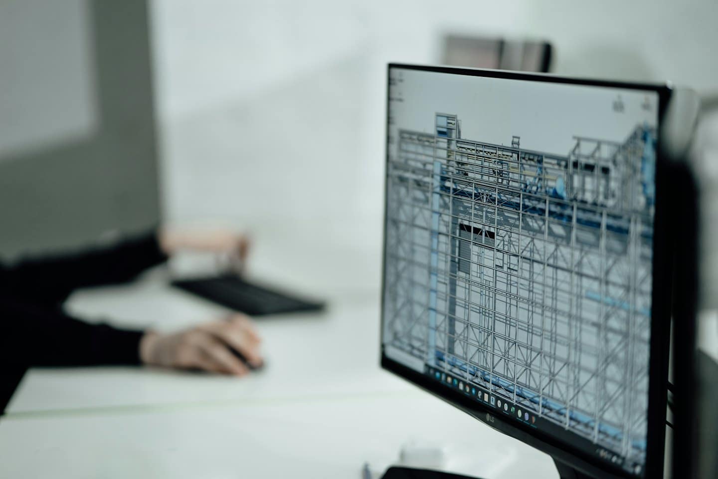 Monitor del computer mostra un modello 3D wireframe con mani sulla tastiera.